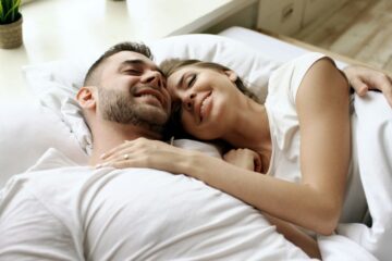 Casal abraçado na cama representando aftercare e cuidado depois do sexo